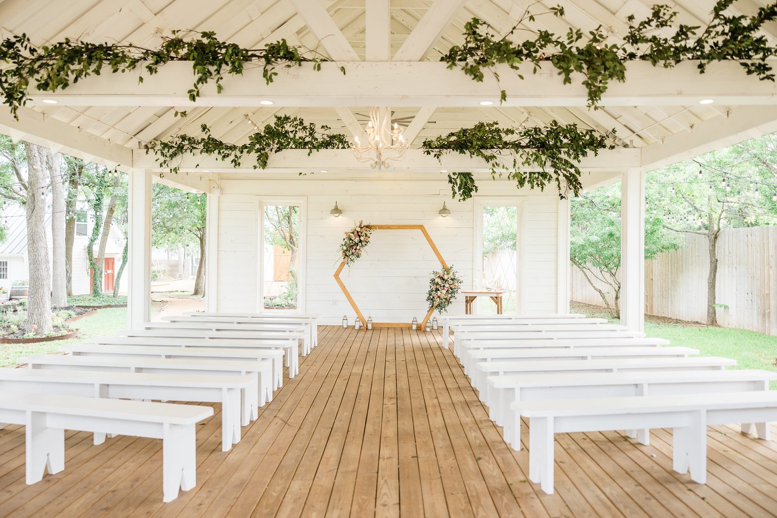 The white open-air chapel at The Chapel at Gruene, dressed with greenery and a wooden hexagon arch