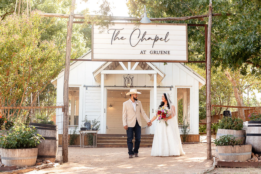 A couple holding hands in front of The Chapel at Gruene